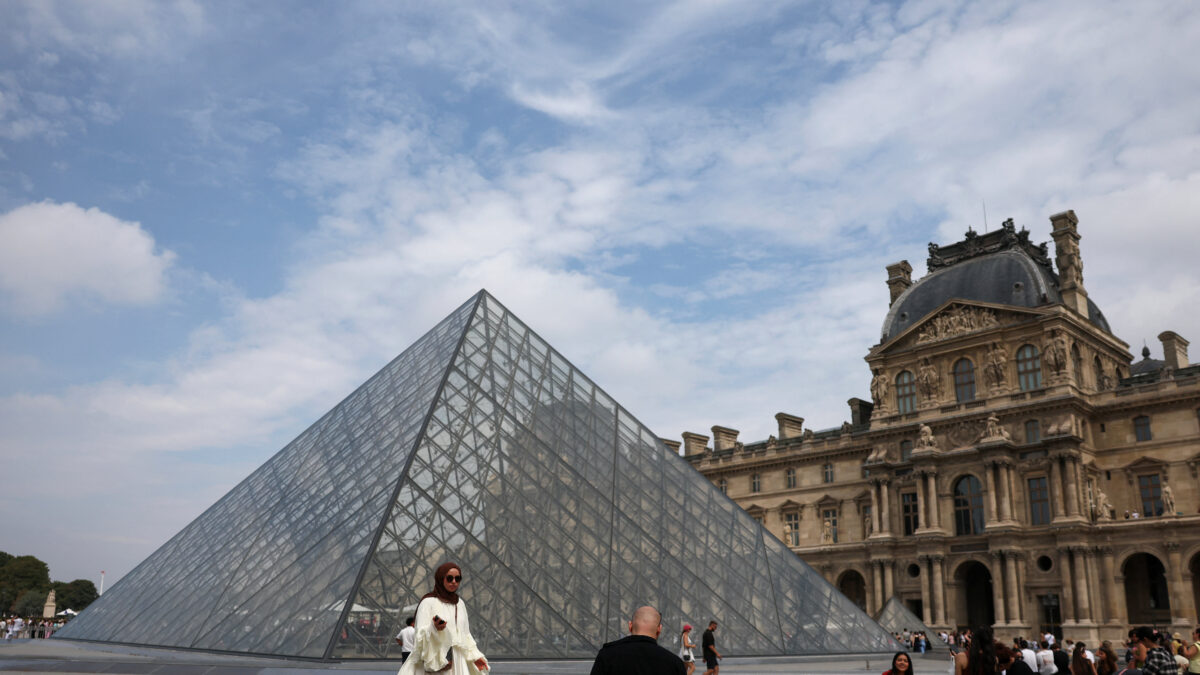 Tourists pose for pictures in front of the glass Pyramid of the Louvre museum on a cloudy summer day in Paris, France, July 17, 2026. REUTERS/Yara Nardi