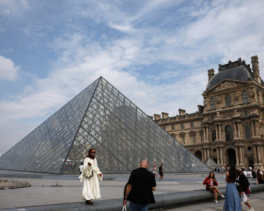 Tourists pose for pictures in front of the glass Pyramid of the Louvre museum on a cloudy summer day in Paris, France, July 17, 2026. REUTERS/Yara Nardi