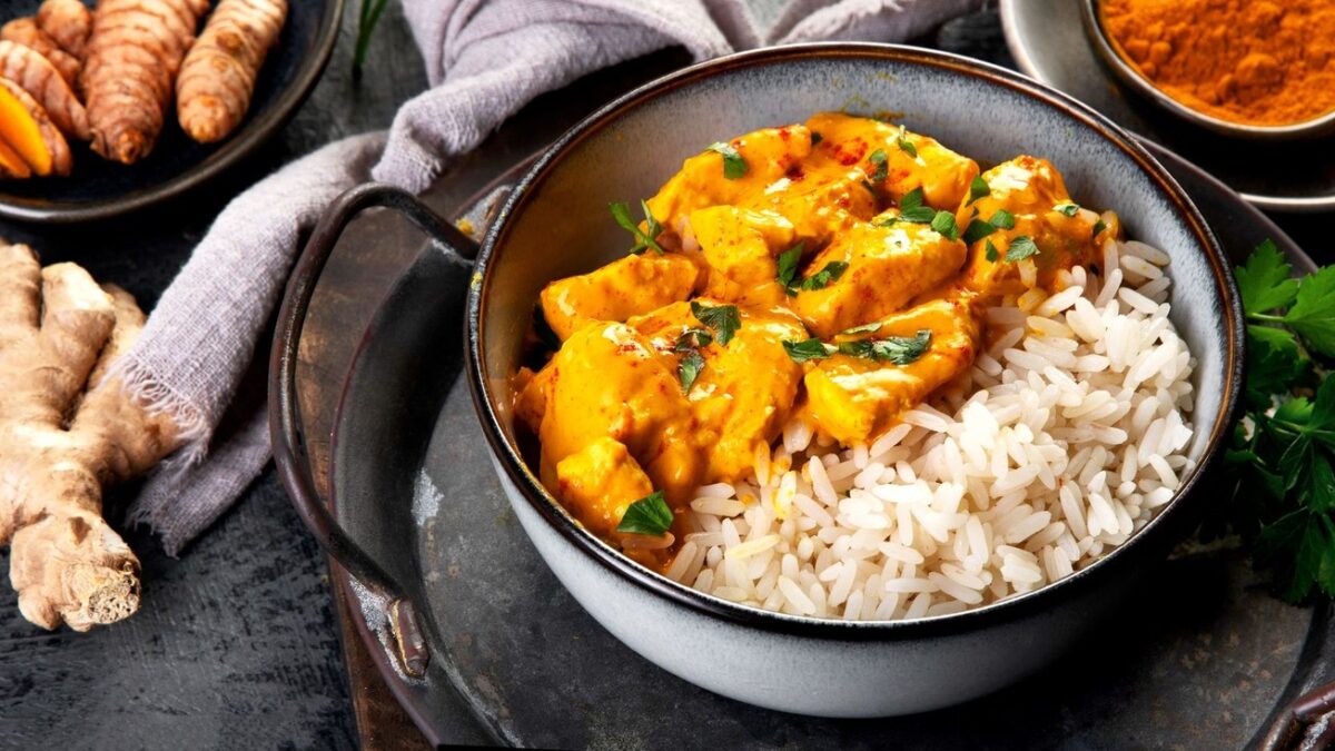 Indian butter chicken curry with basmati rice on dark background