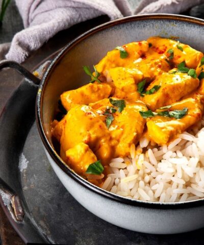 Indian butter chicken curry with basmati rice on dark background