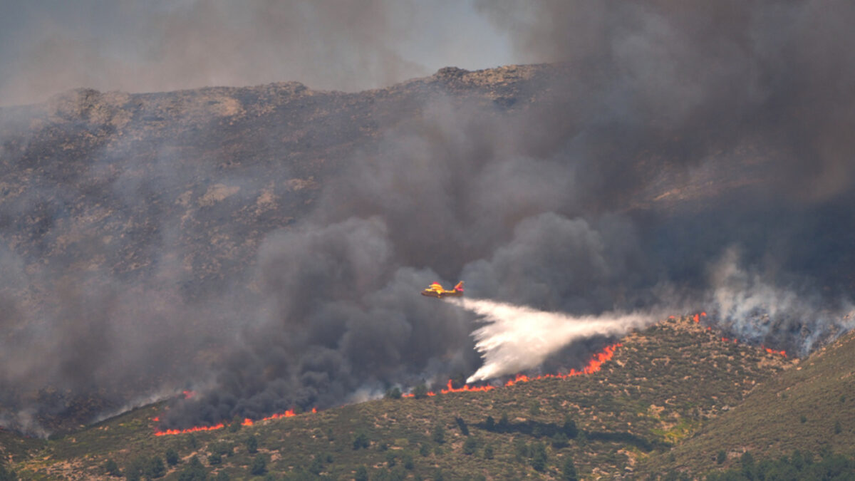 A seaplane drops water onto the fire as a wildfire advances near La Adrada, Ávila province, Spain, Friday, July 24, 2026.