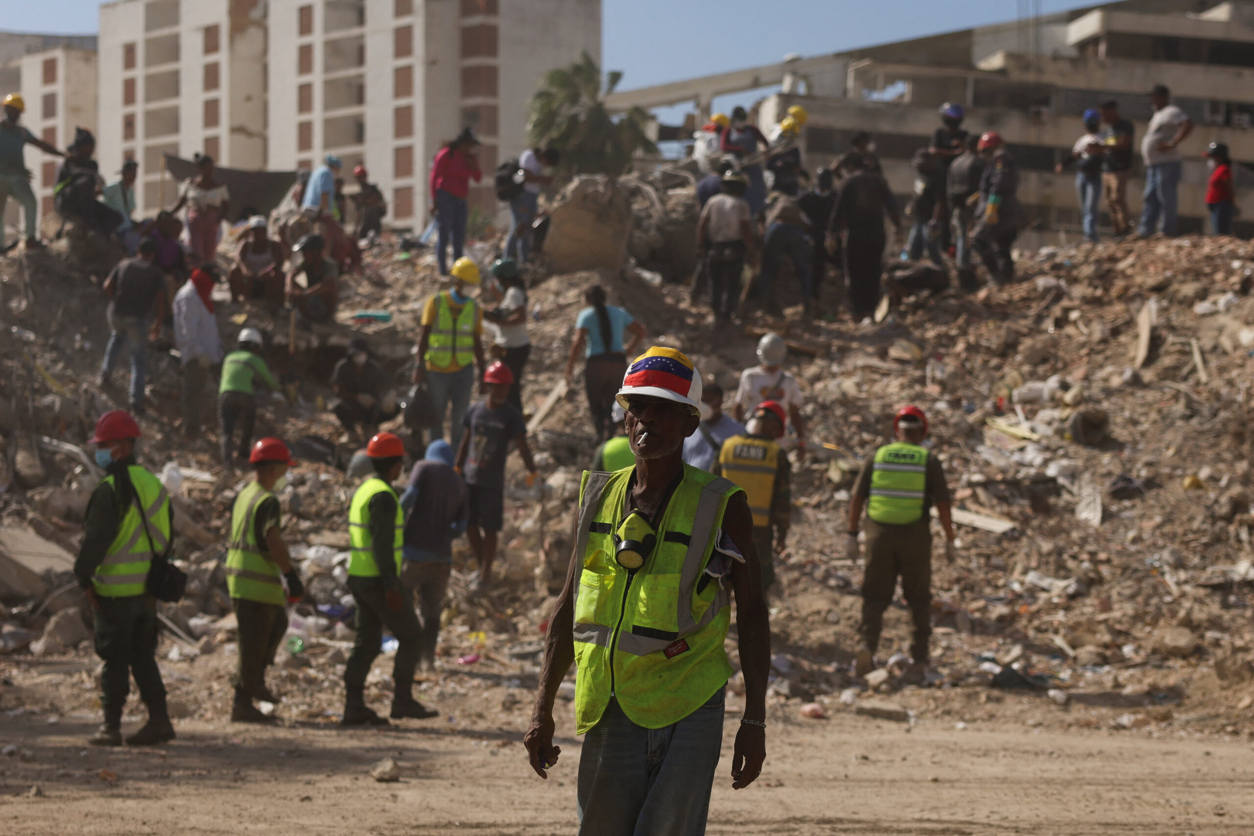 A search and rescue volunteer wearing a Venezuelan flag attached to his helmet searches debris alongside other people, in the aftermath of the June 24 earthquakes, in La Guaira, Venezuela, July 16, 2026. REUTERS