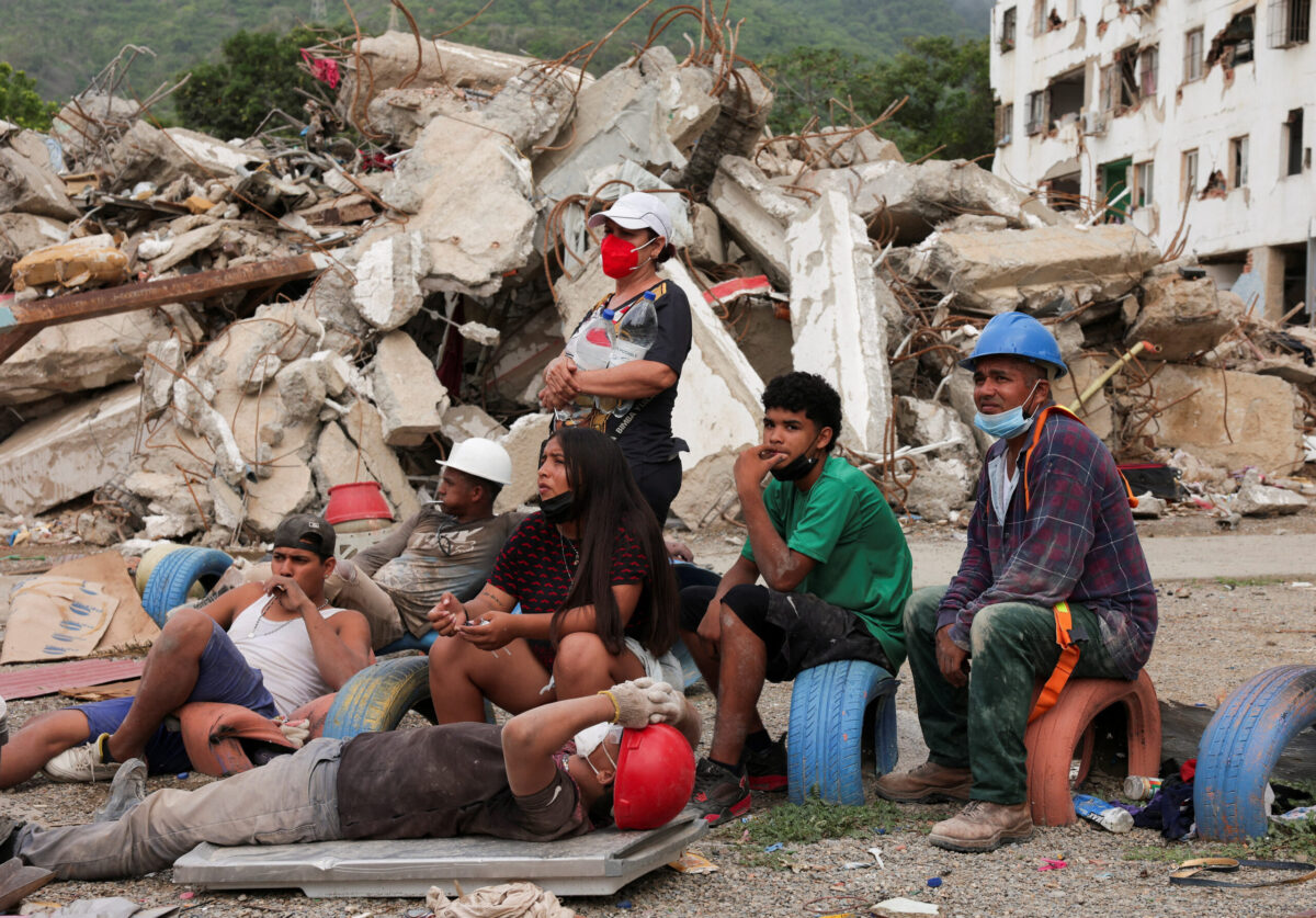 Members of the Davila family rest after spending the day digging a tunnel to search for their loved ones amid debris, in the aftermath of the June 24 earthquakes, at Tanaguarena in La Guaira, Venezuela, July 12, 2026. REUTERS