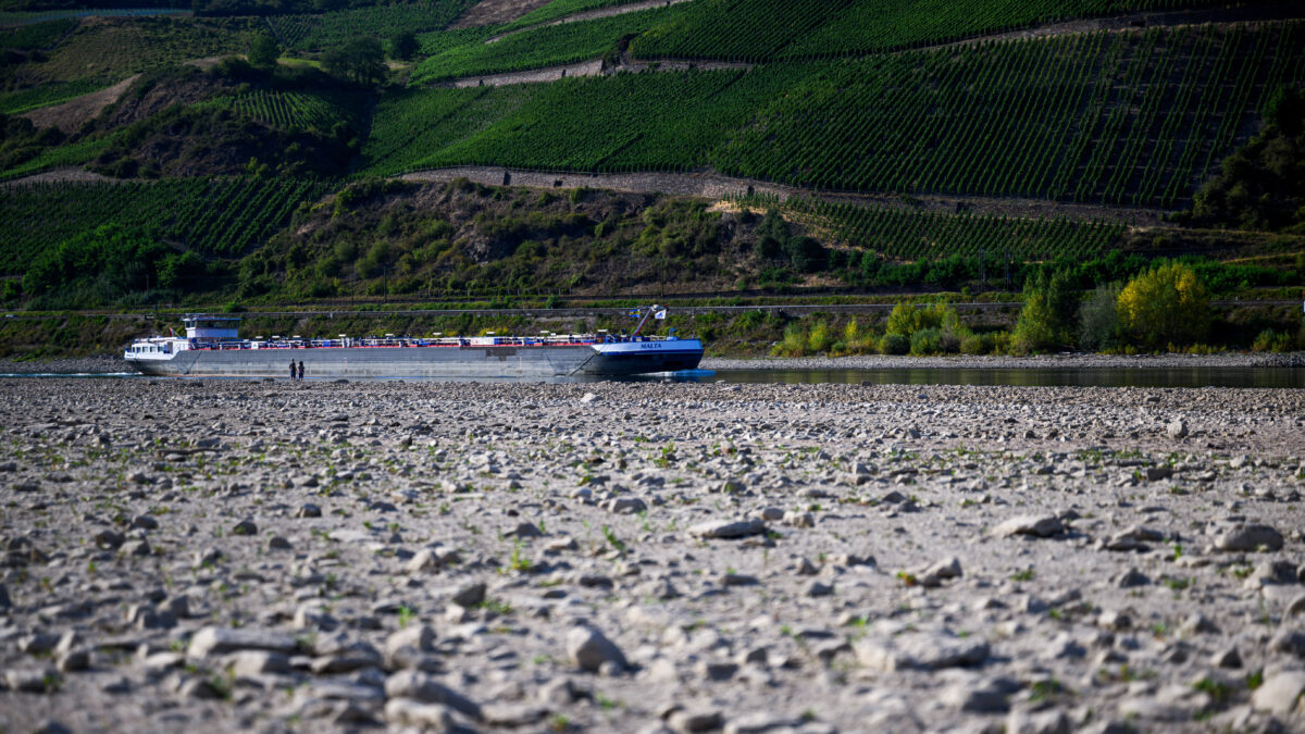 Two people watch a ship pass by on the partially dried riverbed due to low water levels in Osterspai near Koblenz, Germany, August 1, 2026. REUTERS
