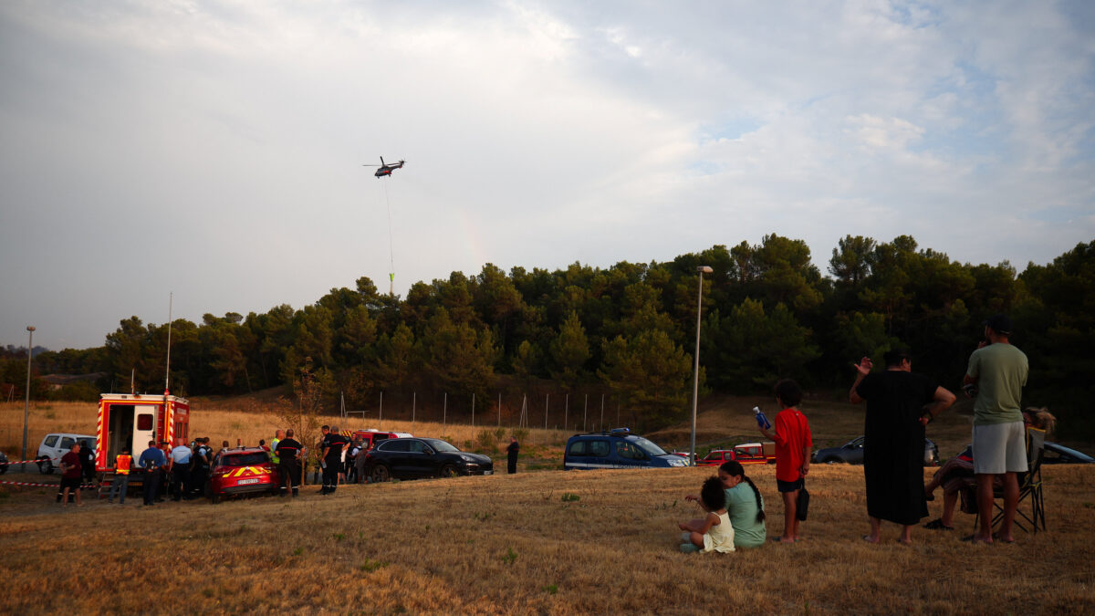 Local residents look on as a firefighting helicopter drops water in Carcassonne, Aude department, amid worsening drought conditions following a heatwave and water shortages across much of France, August 2, 2026.