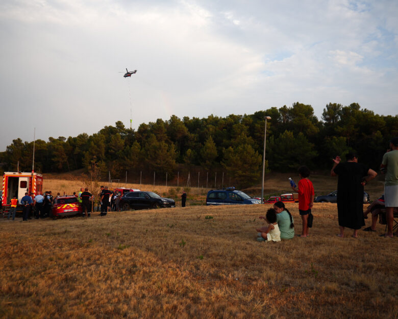 Local residents look on as a firefighting helicopter drops water in Carcassonne, Aude department, amid worsening drought conditions following a heatwave and water shortages across much of France, August 2, 2026.