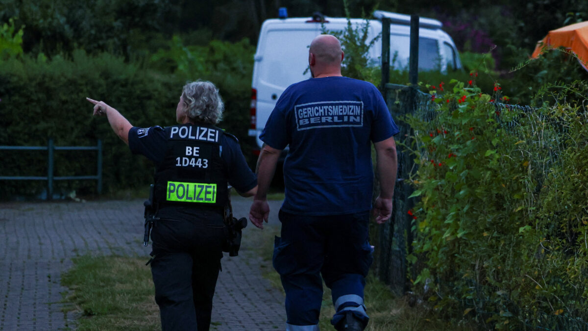 Forensic medicine expert walks with a police officer at an allotment garden complex in the Berlin suburb of Spandau after a known Islamist, suspected of ramming a minivan into a crowd near Berlin's annual Christopher Street Day Pride parade on Saturday evening, was shot and killed in a police operation, in Berlin, Germany, July 26, 2026. REUTERS/Christian Mang