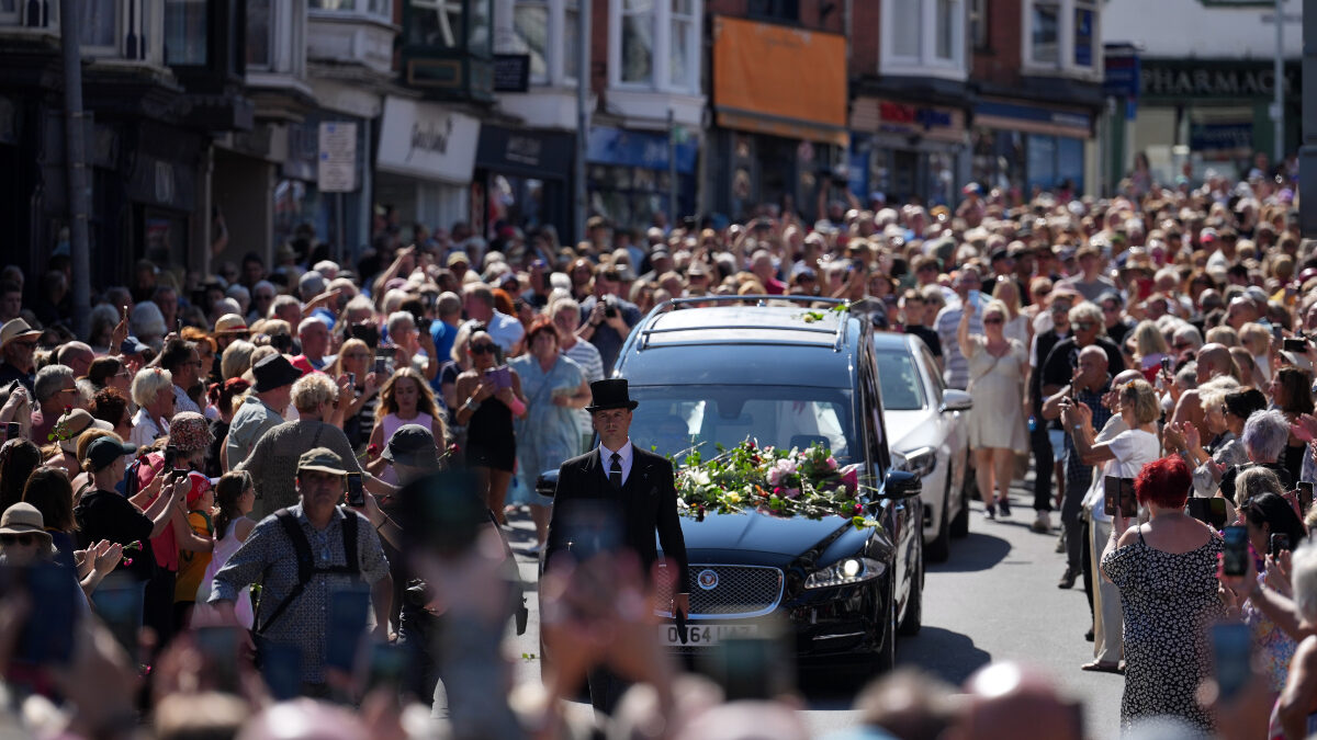 Fans of singer Bonnie Tyler line the streets as her coffin is transported in a hearse back to her former home ahead of her funeral, in Mumbles, Wales, Saturday, Aug. 15, 2026. The Total Eclipse Of The Heart musician, whose real name was Gaynor Hopkins, died in hospital in Portugal on July 8 at the age of 75.