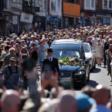 Fans of singer Bonnie Tyler line the streets as her coffin is transported in a hearse back to her former home ahead of her funeral, in Mumbles, Wales, Saturday, Aug. 15, 2026. The Total Eclipse Of The Heart musician, whose real name was Gaynor Hopkins, died in hospital in Portugal on July 8 at the age of 75.