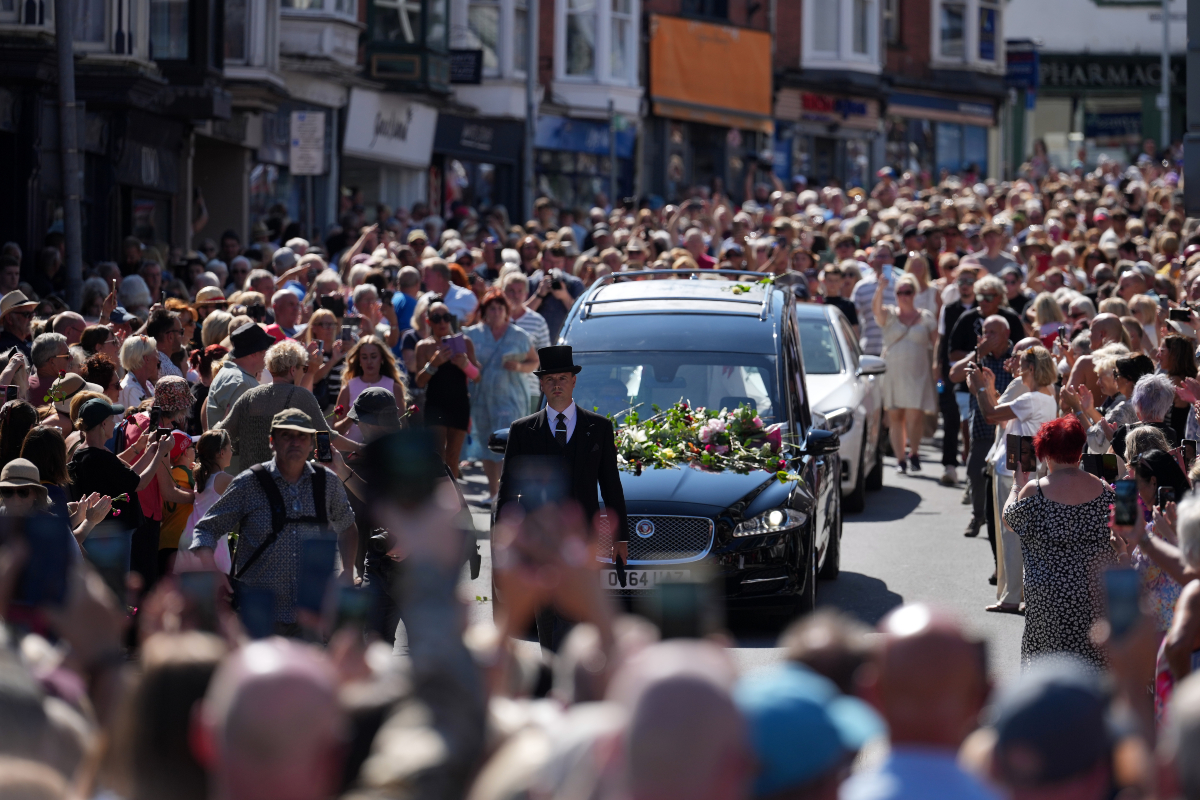 Fans of singer Bonnie Tyler line the streets as her coffin is transported in a hearse back to her former home ahead of her funeral, in Mumbles, Wales, Saturday, Aug. 15, 2026. The Total Eclipse Of The Heart musician, whose real name was Gaynor Hopkins, died in hospital in Portugal on July 8 at the age of 75.