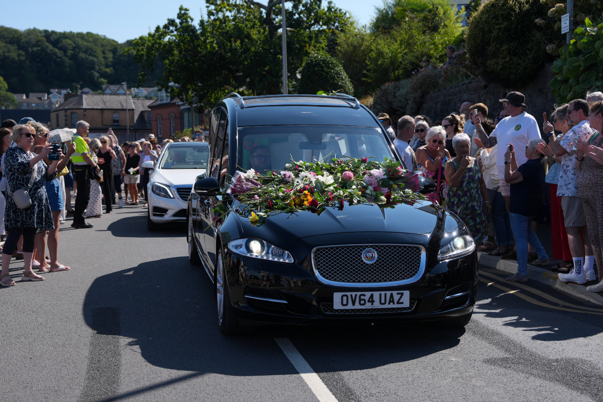 Fans of singer Bonnie Tyler line the streets as her coffin is transported in a hearse back to her former home ahead of her funeral, in Mumbles, Wales, Saturday, Aug. 15, 2026.