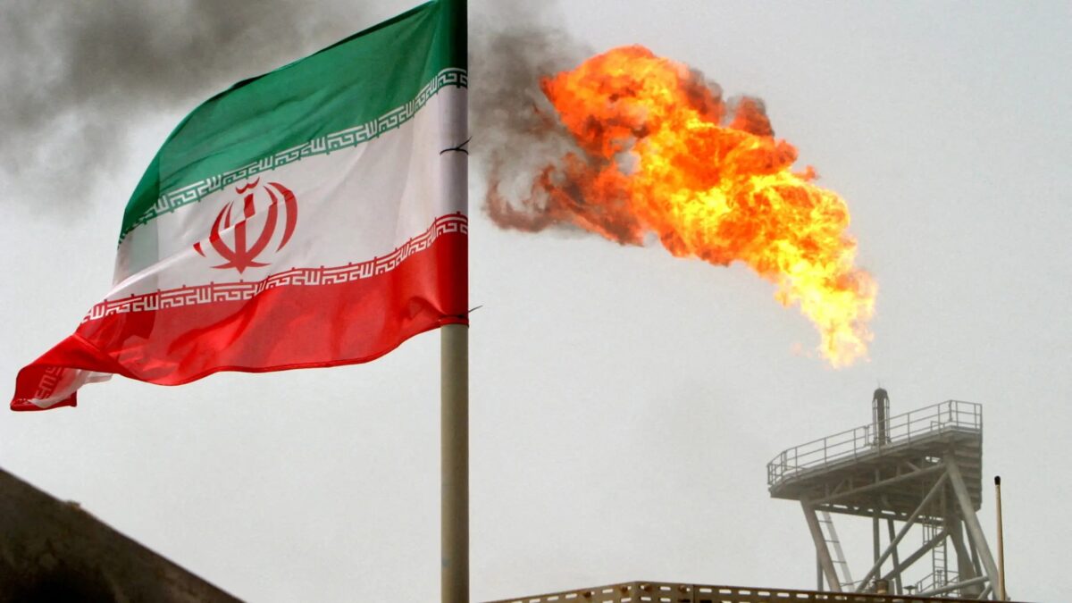 FILE PHOTO: A gas flare on an oil production platform is seen alongside an Iranian flag in the Gulf July 25, 2005.