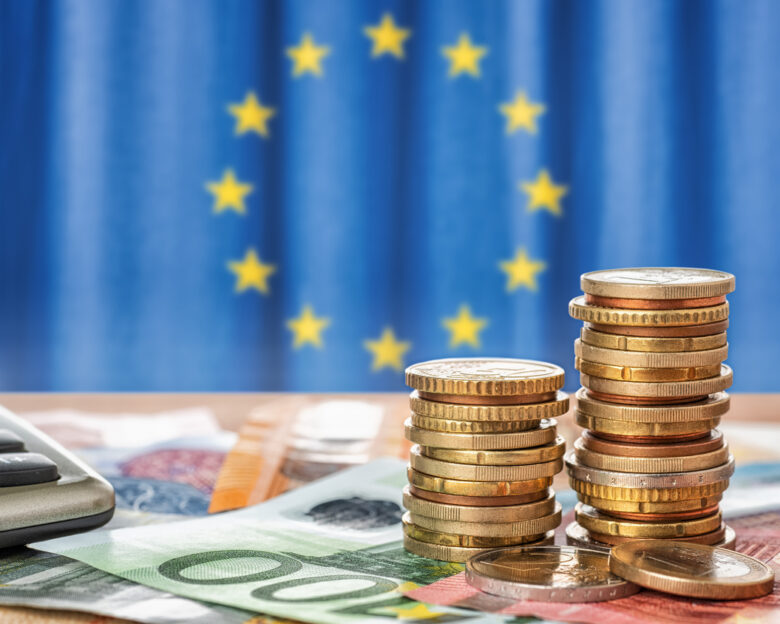 Banknotes and coins in front of the flag of the European Union