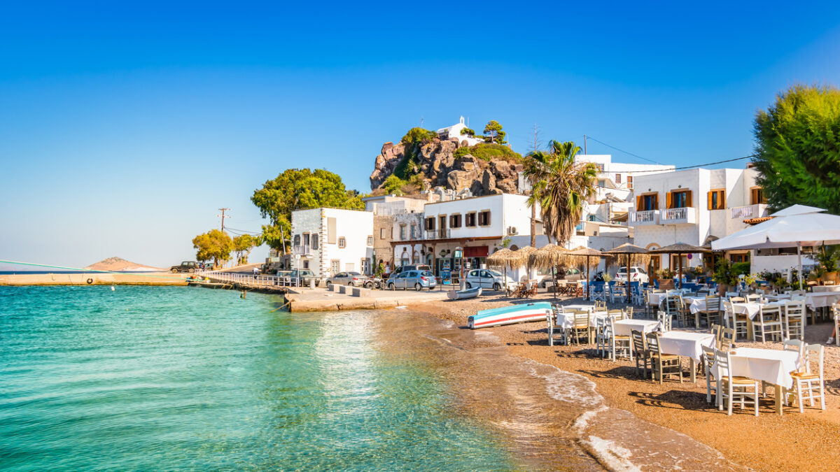 Bright and colorful horizontal image of Skala town. Clear blue sky and small beach close to the harbor of Patmos, Greece.