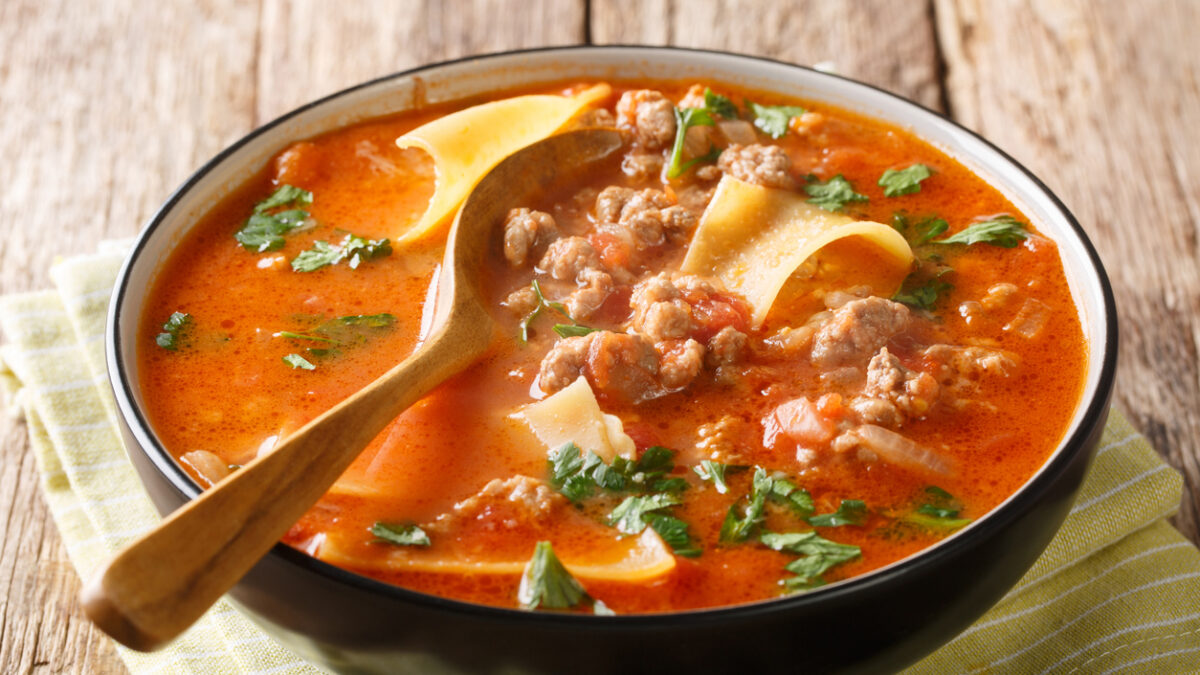Portion of rich lasagna soup close-up in a plate on the table. horizontal