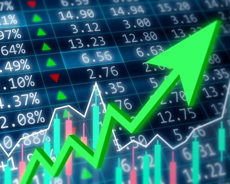 Stock market, financial and business concept. Financial data on a monitor with green arrow going up and red, green candle stick graph chart on dark background