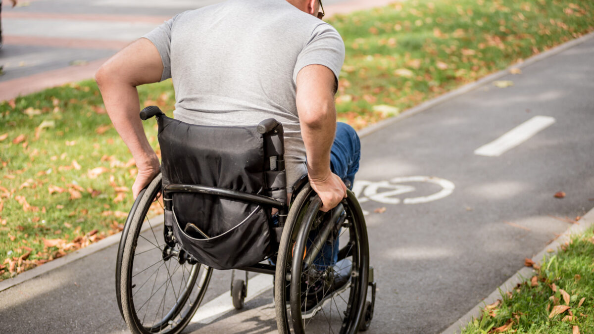 Handicapped man in wheelchair walk at the park alley.