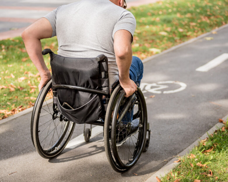 Handicapped man in wheelchair walk at the park alley.