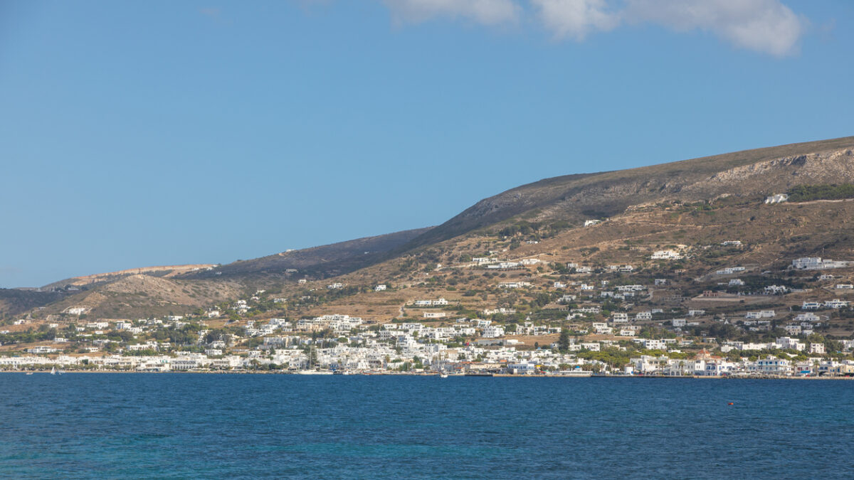 Rocky coast of the island of Paros. A white, traditional building in the background. Greece.