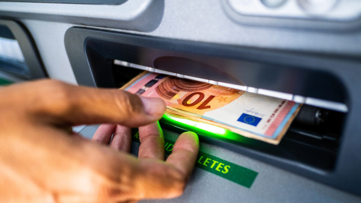 Close-up of the hand of a person withdrawing euro cash from an ATM machine