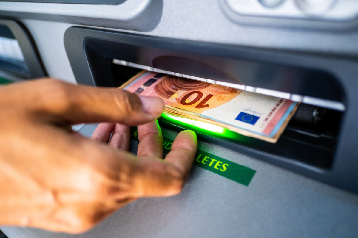 Close-up of the hand of a person withdrawing euro cash from an ATM machine