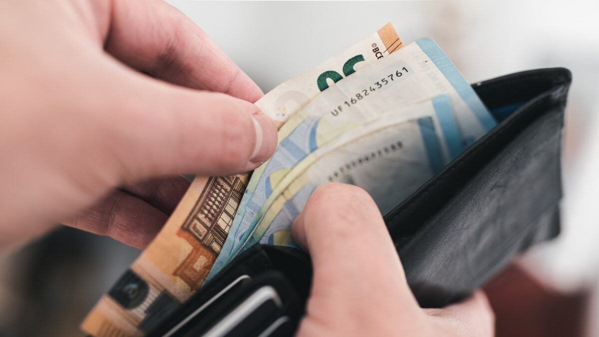 close-up view of hands taking money out of a wallet, spending cash concept