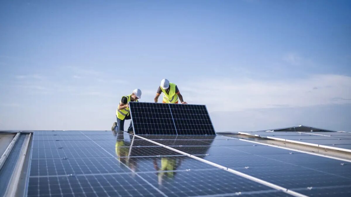 Team of two engineers installing solar panels on industrial factory roof