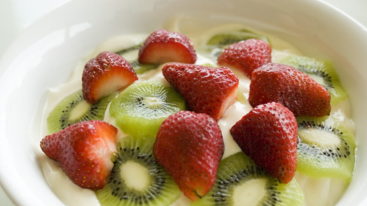 large bowl of yoghurt with sliced fresh fruit on top