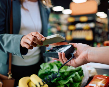 Close up of supermarket customer using cell phone app while paying at cash register.