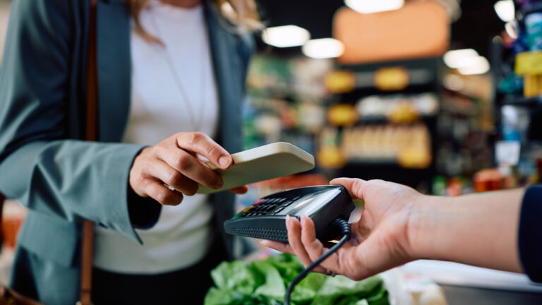 Close up of supermarket customer using cell phone app while paying at cash register.