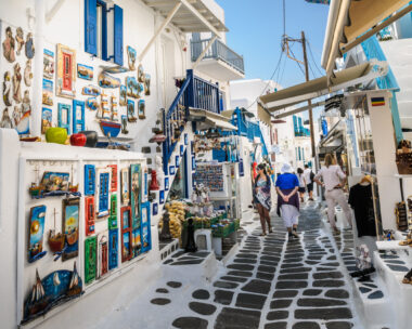 Mykonos, Greece-May 8, 2018-Shoppers explore the narrow alleys of Mykonos Town where colorful merchandise is displayed in hopes of catching a tourists eye.