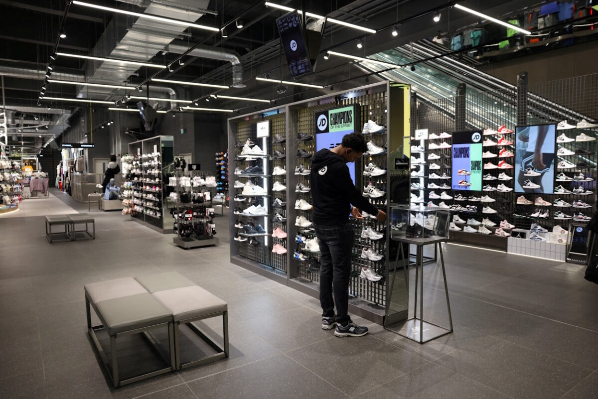 FILE PHOTO: A worker adjusts sneakers on display at the JD Sports store at Westfield Stratford City in London, Britain,