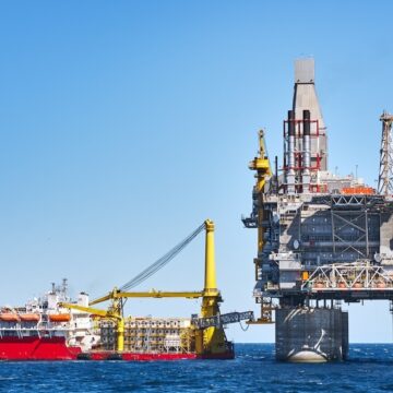 Oil rig and support vessel on offshore area near Sakhalin island. Blue sky background