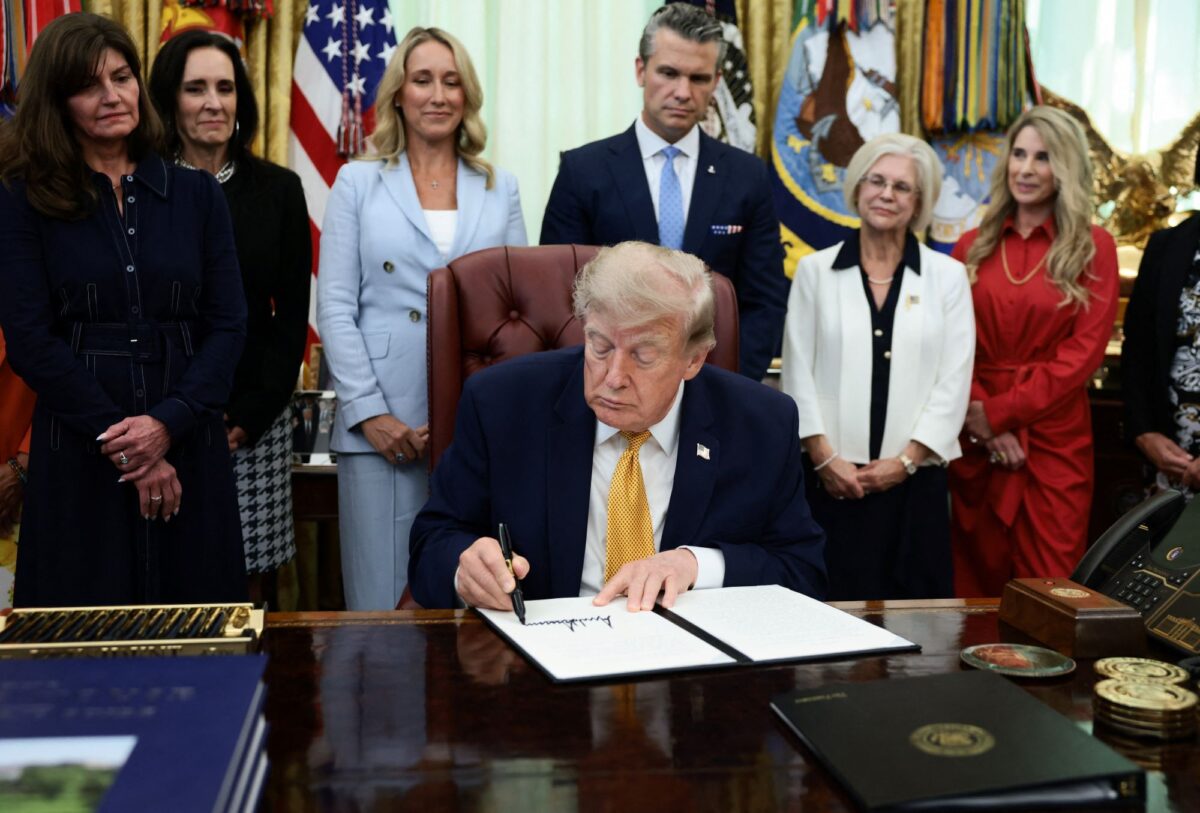 U.S. President Donald Trump signs an executive order establishing the President's Military Spouse Commission to be chaired by Jennifer Rauchet, wife of Secretary of Defense Pete Hegseth, in the Oval Office at the White House in Washington, D.C., U.S., August 3, 2026. REUTERS