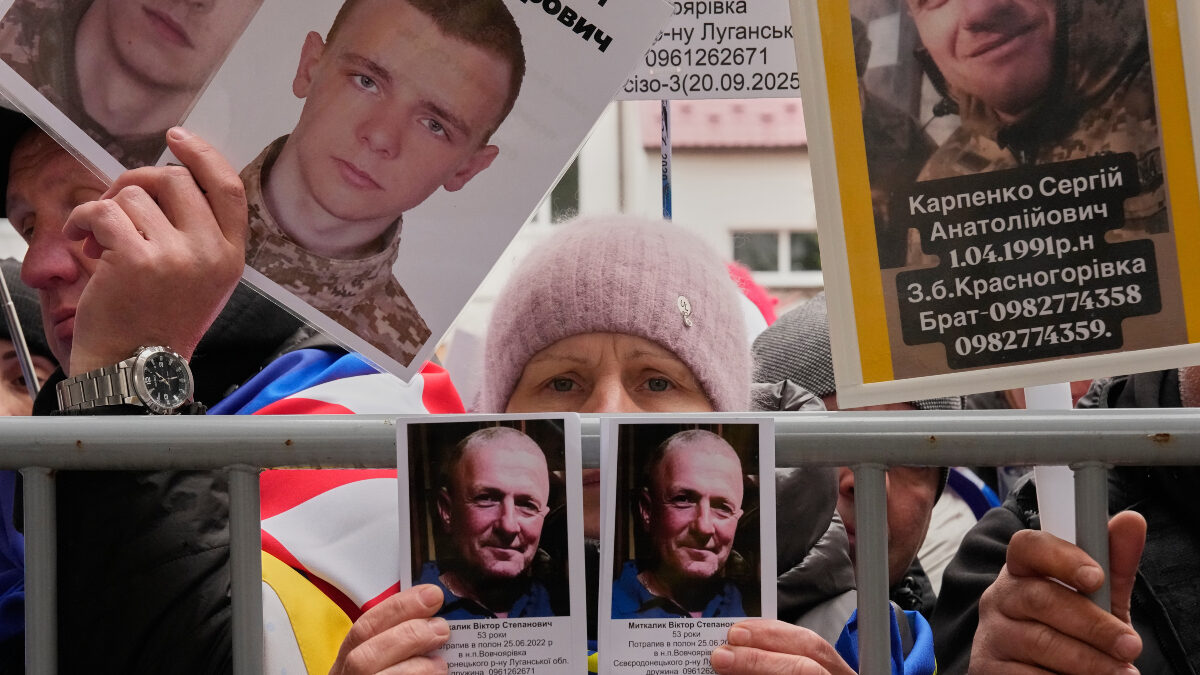 People hold photos of their missed relatives as Ukrainian soldiers return from captivity during a POW exchange between Russia and Ukraine in Chernyhiv region, Ukraine, Saturday, April 11, 2026.