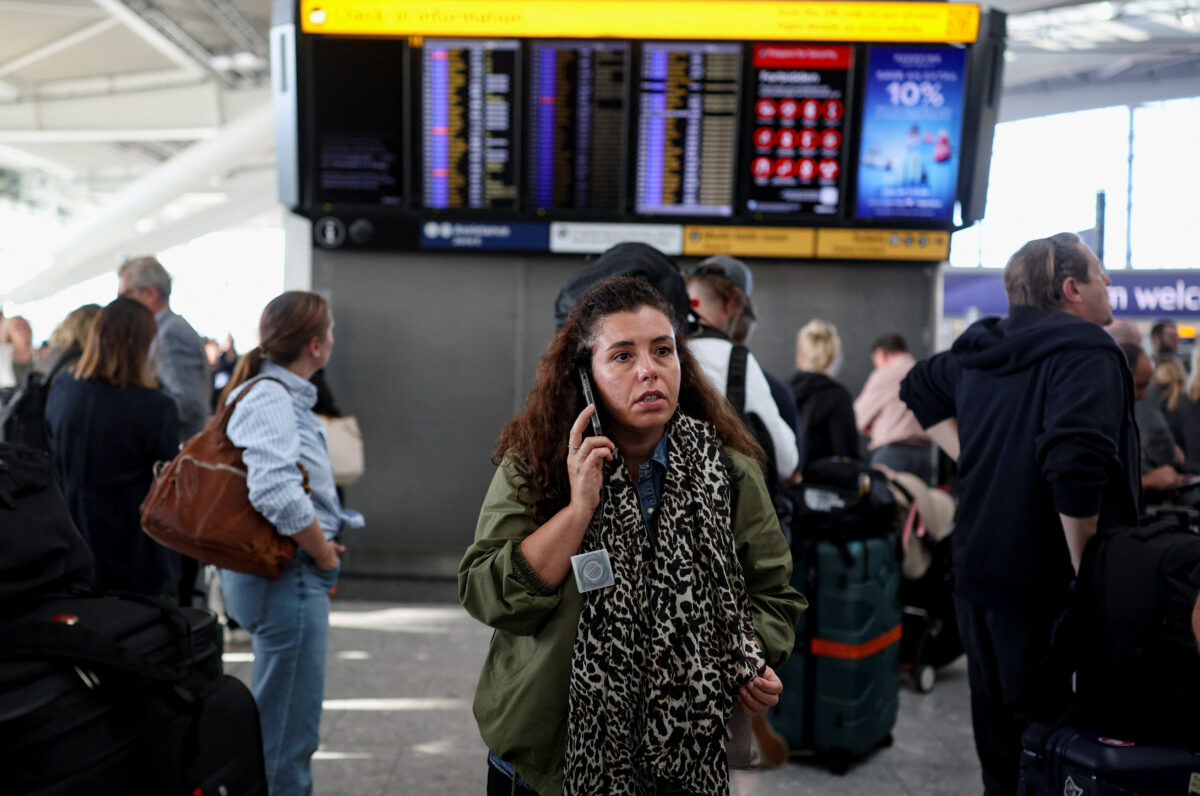 A passenger uses a mobile phone while others look at a departure board displaying cancelled flights at Heathrow Airport's Terminal 5 in London, Britain, September 8, 2026. Some departing flights at major British airports were disrupted on Tuesday after air traffic control provider NATS experienced a technical issue, with Heathrow, Gatwick, Manchester and Stansted among the airports affected by restrictions and delays. REUTERS