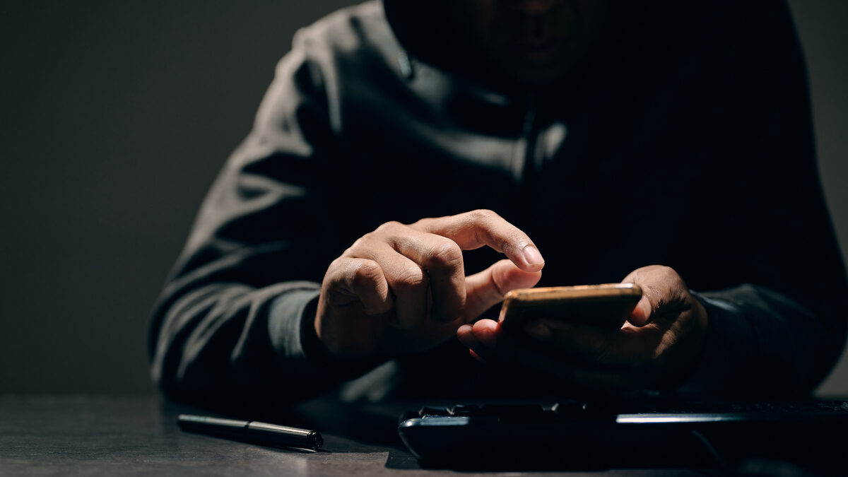 Hacker, thief is using their fingers to press passwords to break into personal data on smartphones. Concept of personal data hacking and financial hacking.