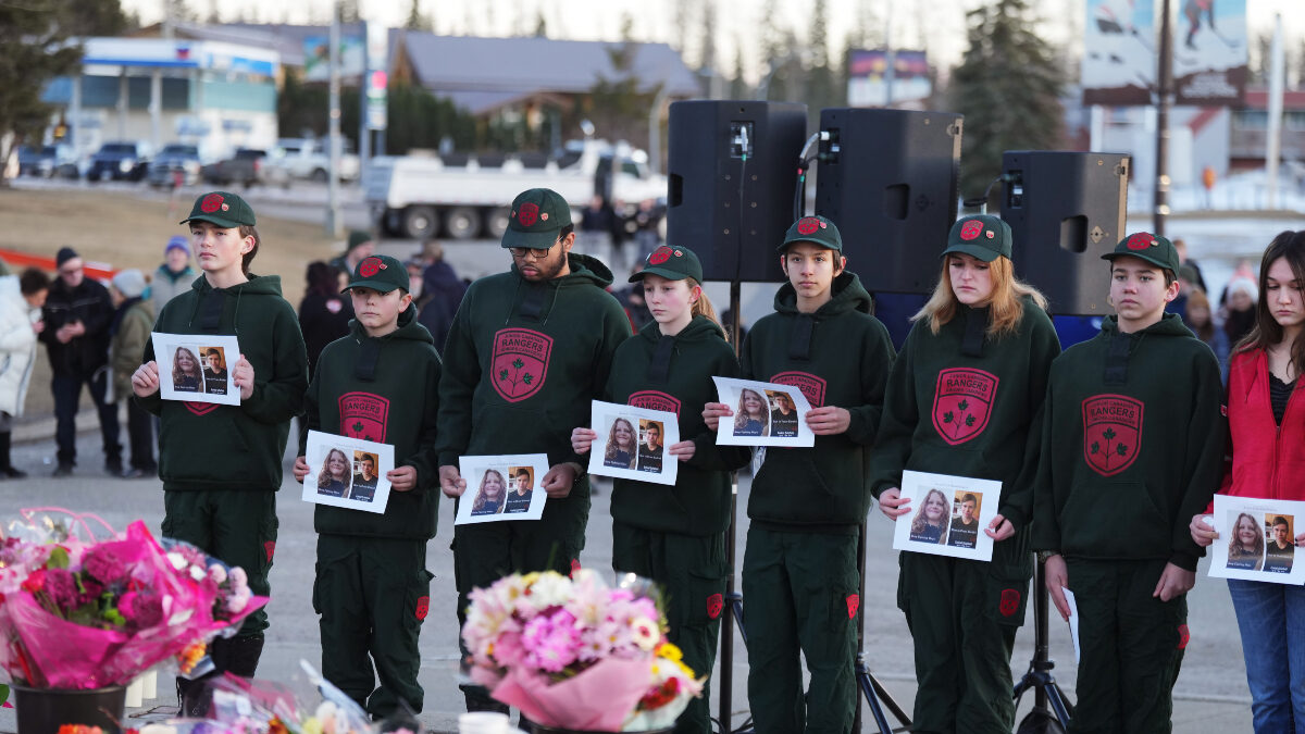 People hold photos of victims to a vigil for the victims of a mass shooting, in Tumbler Ridge, B.C., Friday, Feb. 13, 2026.