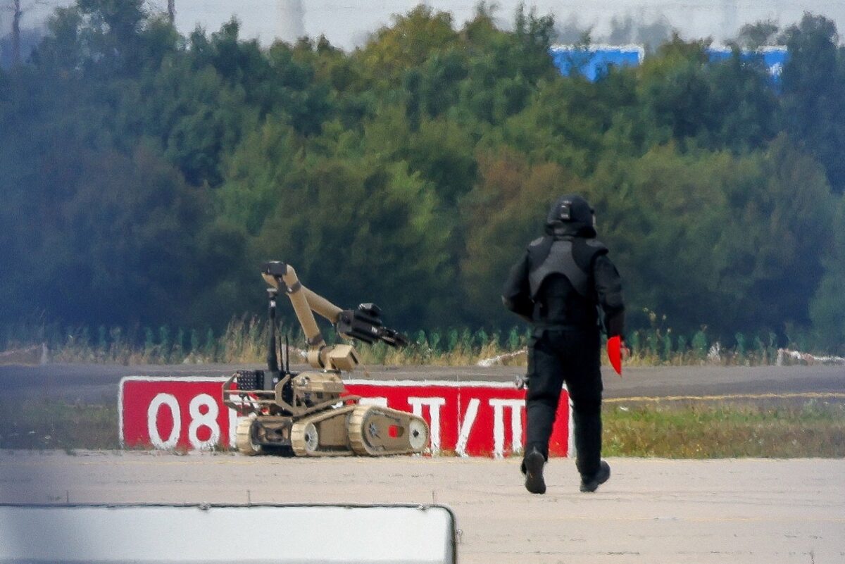 FILE PHOTO: A police officer in protective clothing walks next to an explosive-disarming robot (EOD) at Leipzig