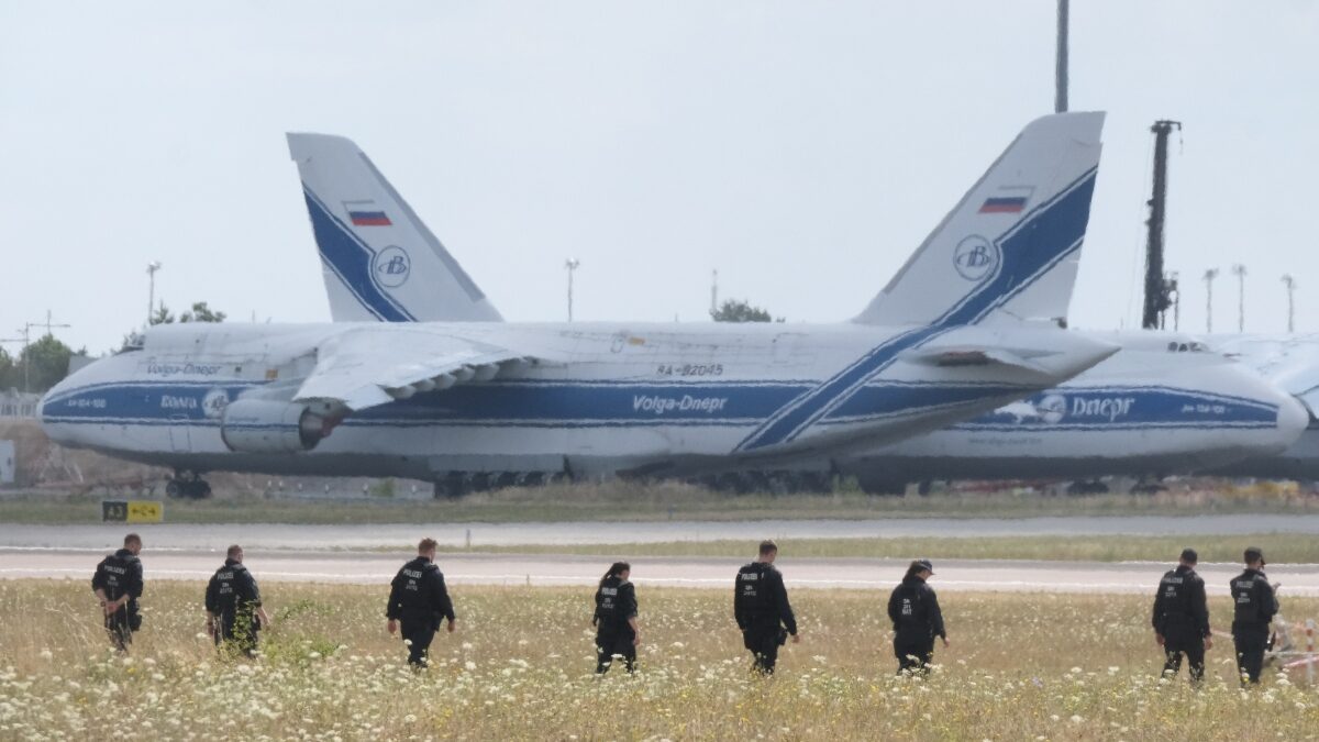 Police officers are walking across a field on the grounds of Leipzig Airport