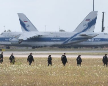 Police officers are walking across a field on the grounds of Leipzig Airport