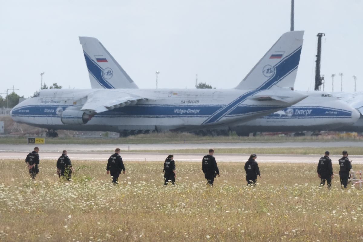 Police officers are walking across a field on the grounds of Leipzig Airport