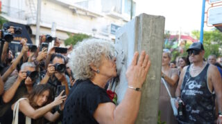 Η μητέρα του Παύλου Φύσσα, Μάγδα Φύσσα κρατώντας ένα κόκκινο τριαντάφυλλο, φιλάει το μνημείο του δολοφονημένου αντιφασίστα μουσικού στην 13η επέτειο του θανάτου του