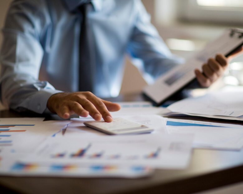 Business accounting concept, Business man using calculator with computer laptop, budget and loan paper in office.