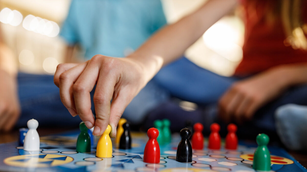 Close up of unrecognizable girl playing ludo game at home.
