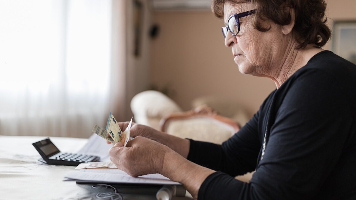 Worried older woman sitting at a table and calculating her expenses
