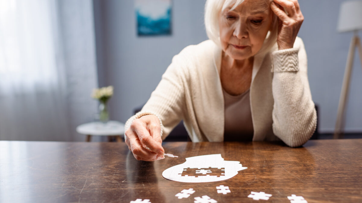 senior woman combining jigsaw puzzle for dementia rehabilitation