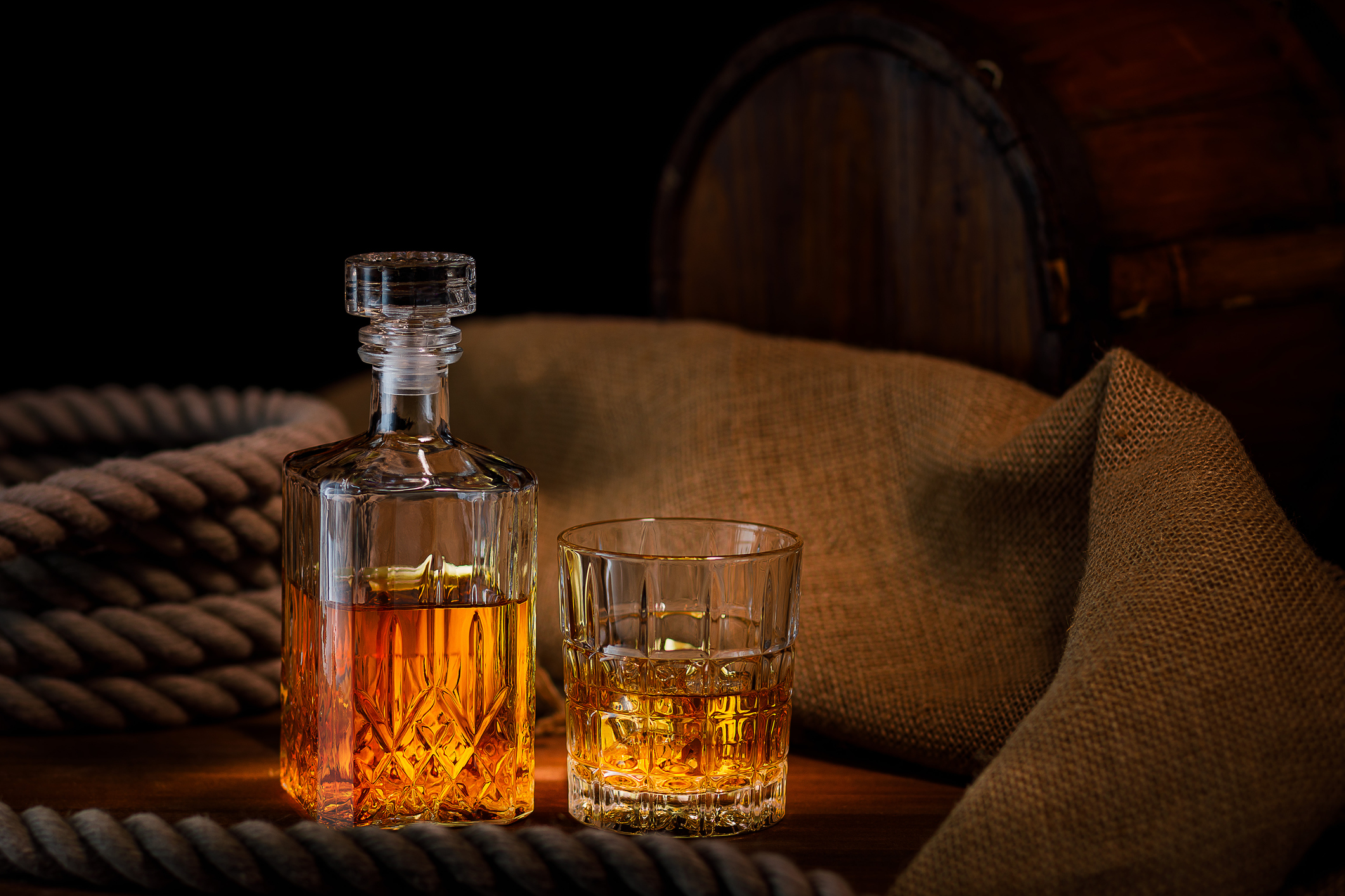 Glass and bottle of whiskey on rustic background