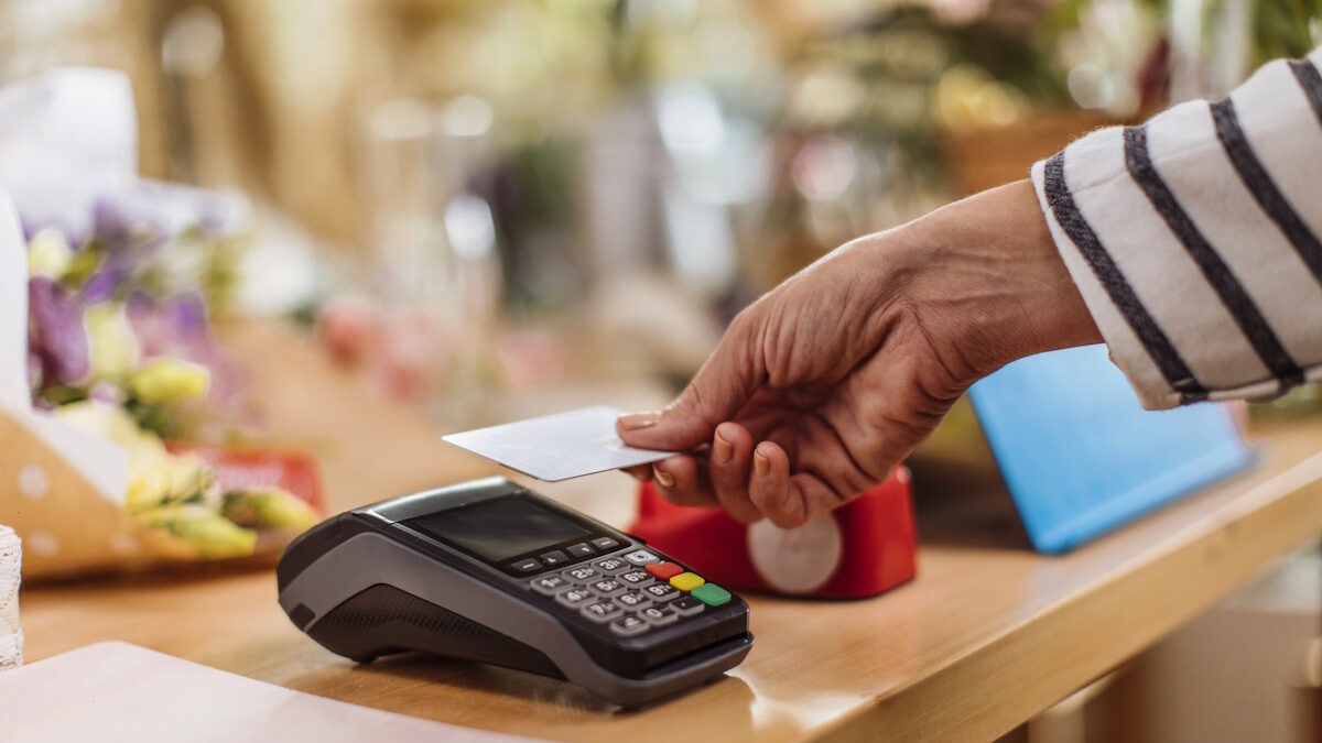 Unrecognizable person making a contactless credit card payment at the flower shop, electronic payments