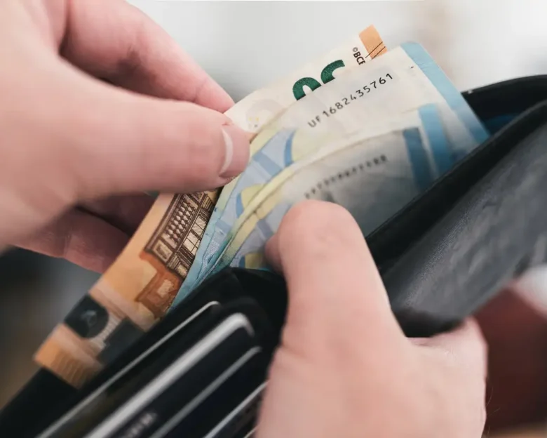 close-up view of hands taking money out of a wallet, spending cash concept